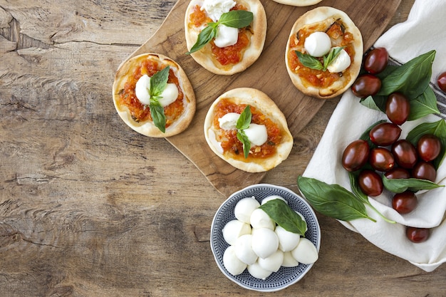 Homemade mini pizzas margarita with tomato, mozzarella and basil