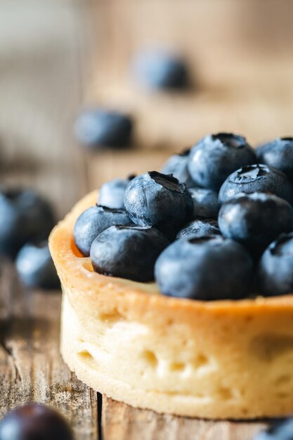 Homemade mini tart with blueberries and whipped cream on a wooden background close up
