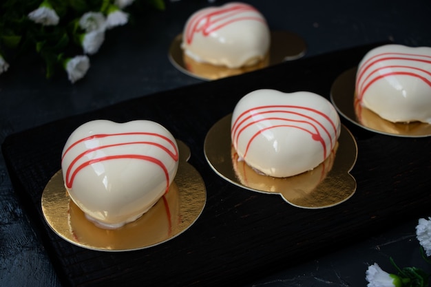 Homemade mousse cakes Hearts with white mirror icing on a dark background