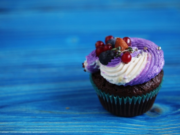 Homemade muffin with berries and mascarpone cheese on blue wooden background