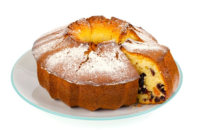 Homemade muffin with dried berries and powdered sugar on plate.