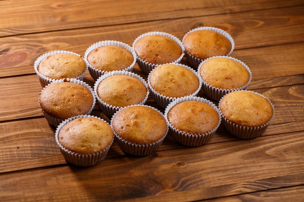 Homemade muffins in paper wrap on wooden board