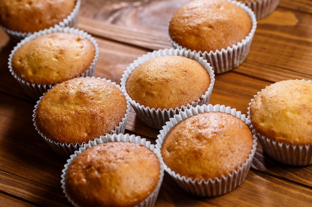 Homemade muffins in paper wrap on wooden board