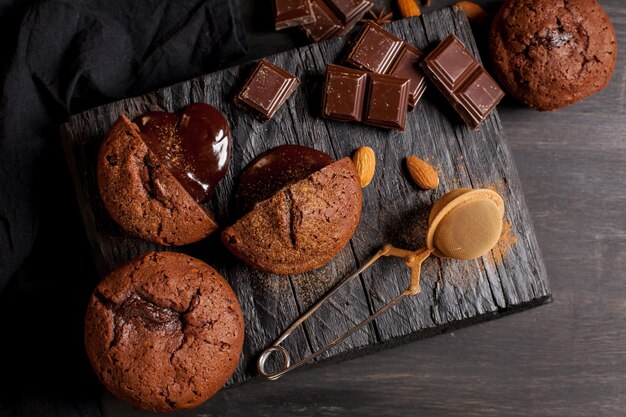 Homemade muffins with chocolate chocolate bars and almonds grains on a black wooden background