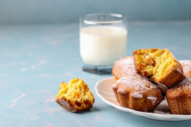 Homemade muffins with dried apricots sprinkled with powdered sugar and a glass of milk