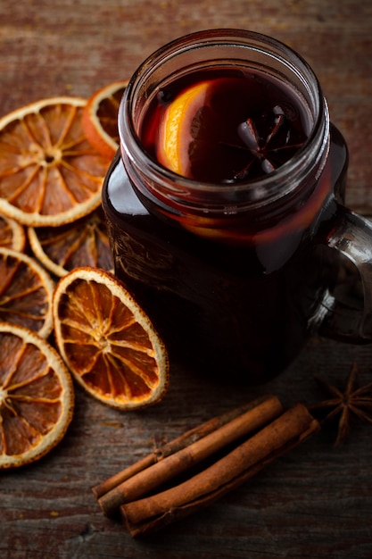 Homemade mulled wine, dried oranges and cinnamon sticks on dark