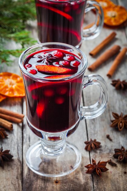 Homemade mulled wine with orange slices cranberries cinnamon and anise on wooden table