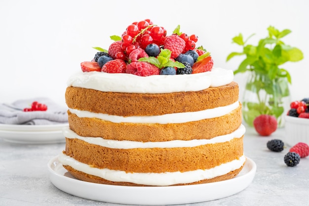 Homemade naked layered vanilla cake with whipped cream and fresh berries Summer cake Copy space