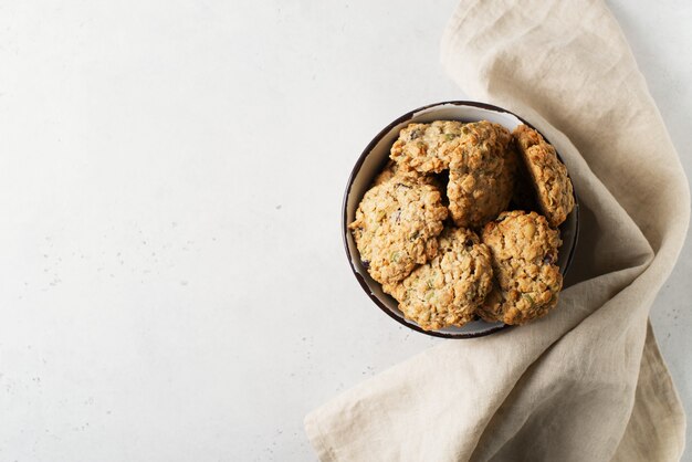 Homemade oat cookies in bowl on white background, healthy snack, copy space