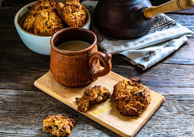 Homemade oatmeal cookies and prepared coffee in a ceramic dish on the kitchen table.