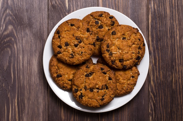 Homemade oatmeal cookies on a white plate. Wooden background