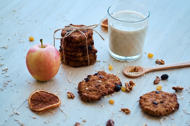 Homemade oatmeal cookies with walnut, raisins and milk on a wooden table