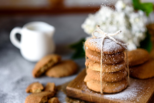 Homemade oatmeal cookies on a wooden cutting board on old table background. Healthy food snack concept