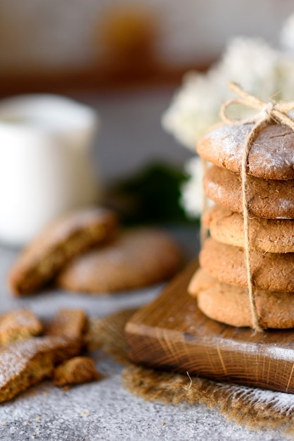 Biscotti di farina d'avena casalinghi su un tagliere di legno sul vecchio fondo della tavola. concetto di snack cibo sano