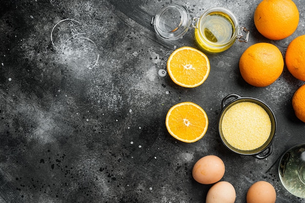 Homemade orange cake ingredients, with eggs and honey set, on black dark stone table background, top view flat lay, with copy space for text