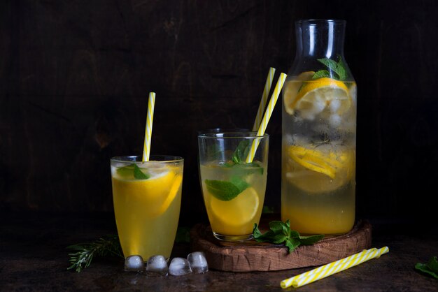 Homemade orange lemonade with citrus and mint on a dark wooden space