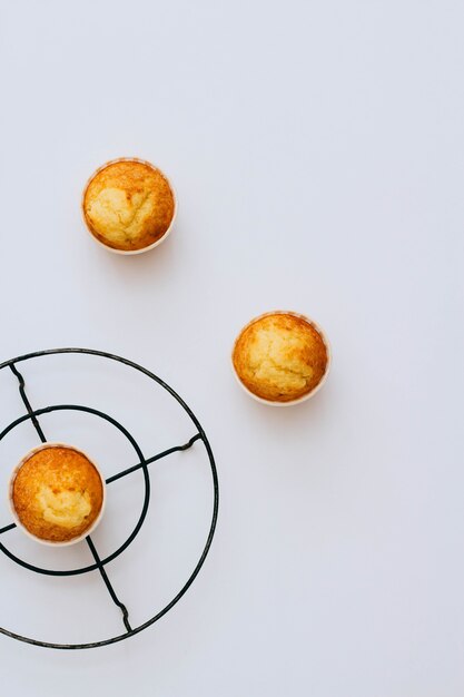 Homemade orange muffins on a metal stand under the hot on a white background.