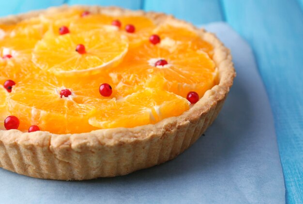 Homemade orange tart on color wooden background