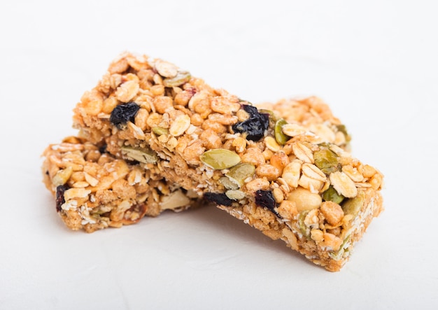 Homemade organic granola cereal bars with nuts and dried fruit on white.