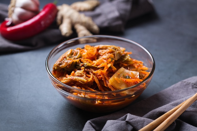 Homemade organic traditional korean kimchi cabbage salad with chopsticks on a dark table. Fermented vegetarian, vegan preserved gut health food concept