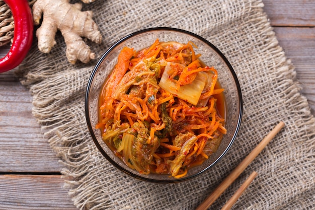 Homemade organic traditional korean kimchi cabbage salad with chopsticks on a wooden table. Fermented vegetarian, vegan preserved gut health food concept