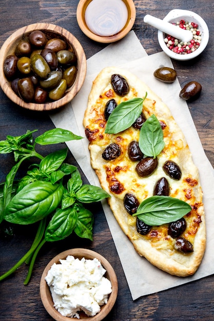 Pizza ovale fatta in casa con olive intere e formaggio vista dall'alto