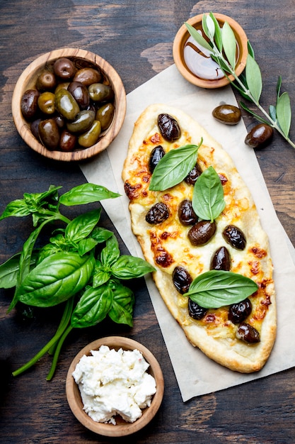 Homemade oval pizza with whole olives and cheese