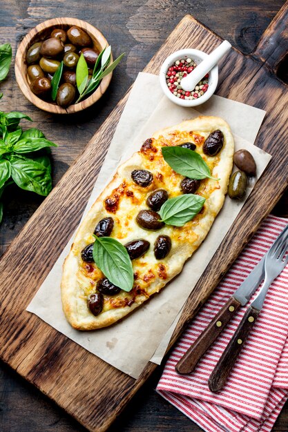 Homemade oval pizza with whole olives and cheese