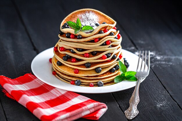 Homemade pancakes with berries, mint and powdered sugar for breakfast