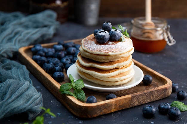 Homemade pancakes with blueberries and powdered sugar on the table close-up.