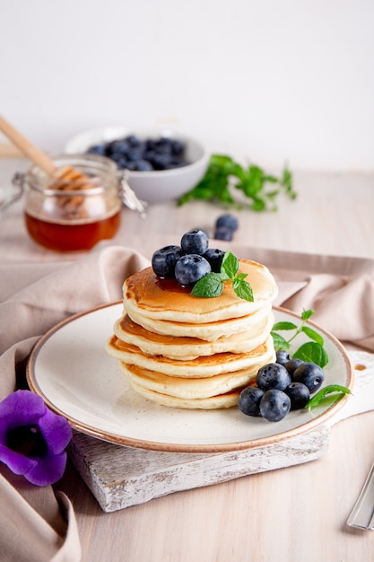 Homemade pancakes with blueberries and powdered sugar on the white table vertical photo.