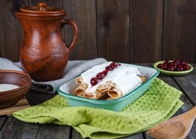 Homemade pancakes with cherries on a wooden table in a rustic style.