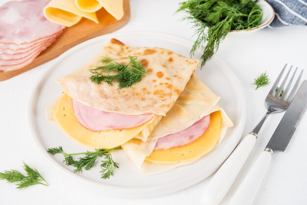 Homemade pancakes with ham and cheese on a white surface, Maslenitsa