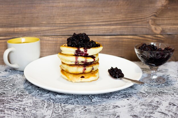 homemade pancakes with jam on a wooden background, blackberry jam, fresh pastries