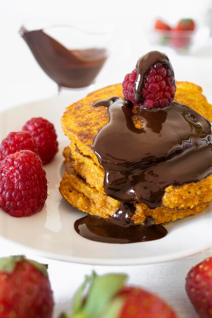 Homemade pancakes with red fruit and melted dark chocolate