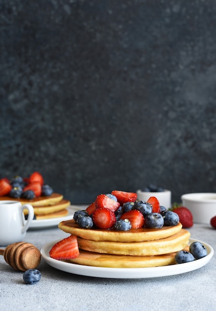 Homemade pancakes with strawberries and blueberries for breakfast on the kitchen table.