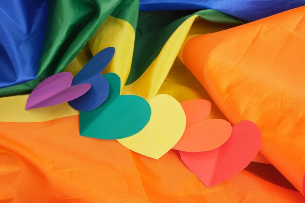 Homemade paper hearts in the colors of the lgbt community pride flag on a large fabric flag, love freedom concept