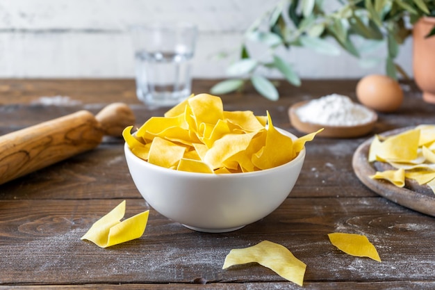 Homemade pasta Maltagliati on cutting board with ingredients