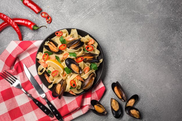 Homemade Pasta Spaghetti with mussels, chilli and parsley on stone background. sea food meal