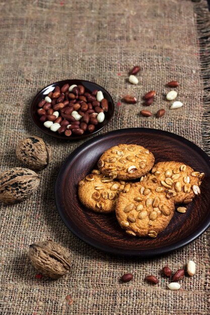 Homemade peanut cookies on a brown plate with raw peanuts in surface