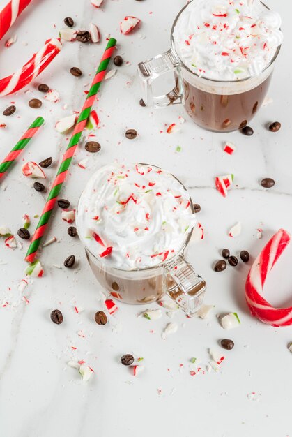 집에서 만든 박하 모카, 사탕 지팡이, 휘핑 크림과 민트 시럽, 흰색 대리석 테이블에 크리스마스 커피 음료