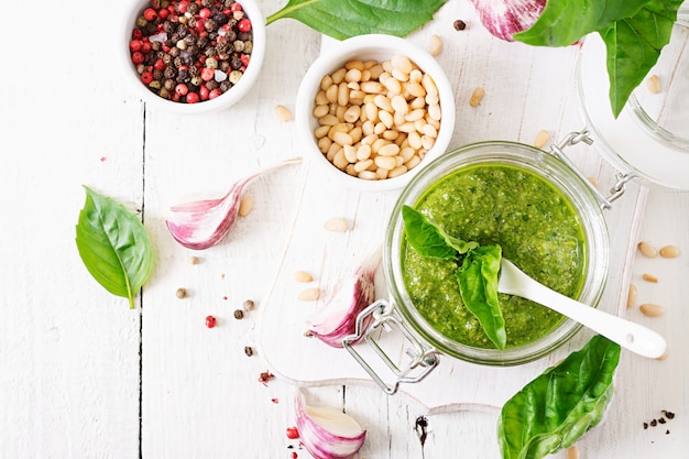 Homemade pesto sauce fresh basil, pine nuts and garlic on white wooden table