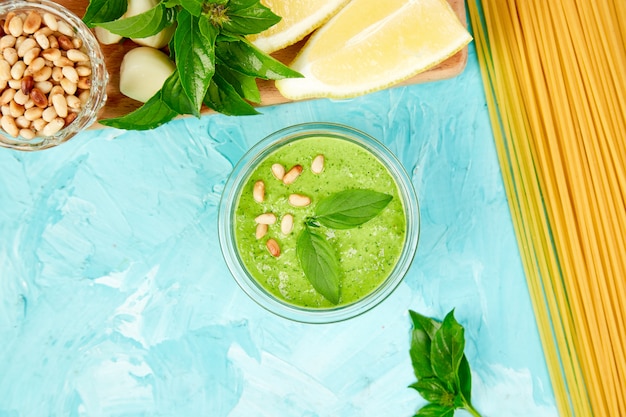 Homemade pesto sauce in glass jar with ingredients.