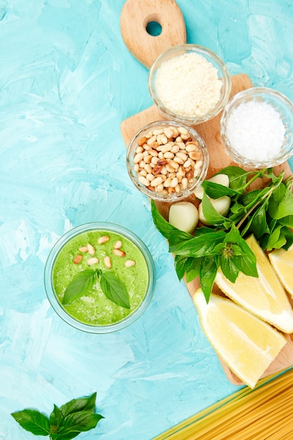 Homemade pesto sauce in glass jar with ingredients.