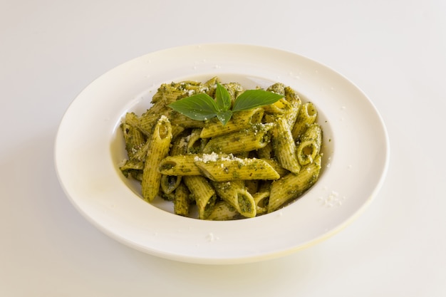 Foto pasta fatta in casa al pesto su sfondo bianco