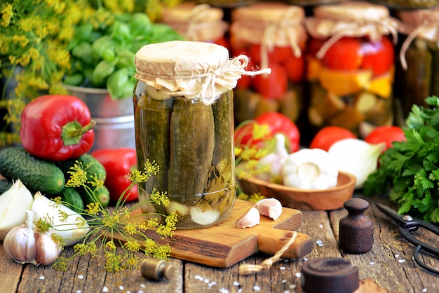 Homemade pickled cucumbers with onions, garlic, pepper and horseradish in a jar on an old wooden background.