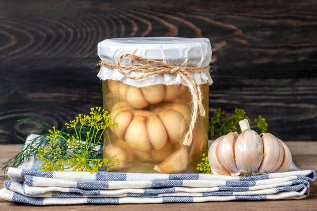 Homemade pickled garlic dill in jars on wooden shelf