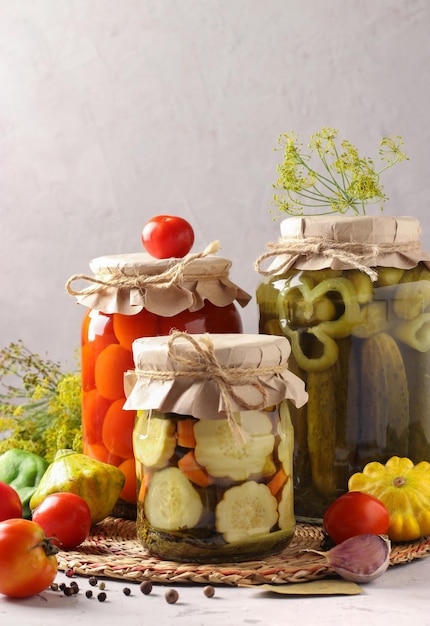 Домашние маринованные помидоры и огурцы патиссон на сером фоне со свежими ингредиентами