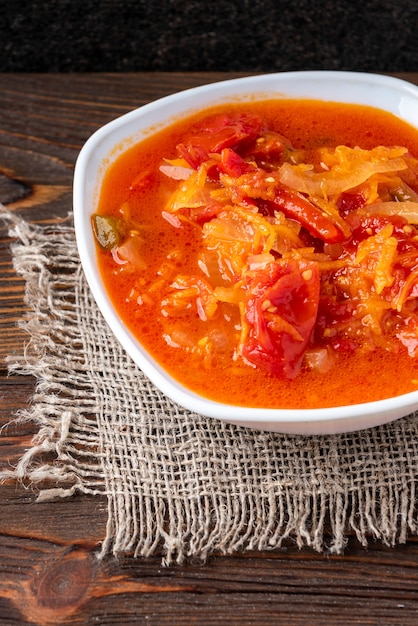 Foto insalata marinata fatta in casa di pomodoro, peperone, cipolla e carota su legno scuro