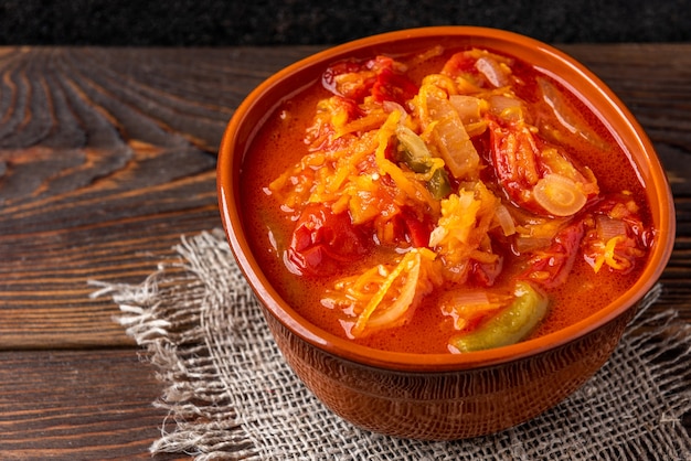 Homemade pickled salad of tomato, pepper, onion and carrot on dark wooden